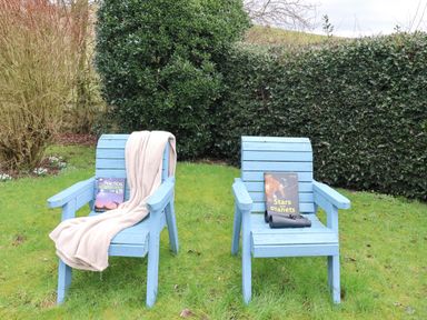 Two blue chairs with books and a telescope in the garden at Petty Knowes Cottage Rochester near Otterburn