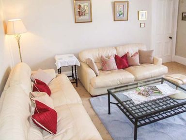 A sitting room with two cream sofas with pillows and a glass coffee table at Bank View in Chirnside