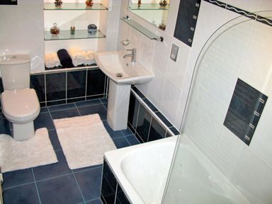 A bathroom with a toilet sink bathtub shelves with towels and decorative items at Bank View in Chirnside