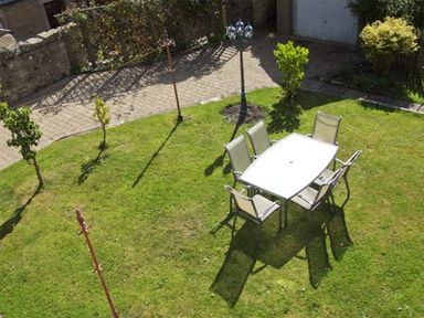 An outdoor area with a glass table and six chairs on a grass lawn with small trees and a lamp post at Bank View in Chirnside