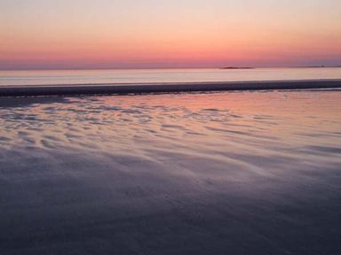 A beach with water and sand at sunset at Bank View in Chirnside