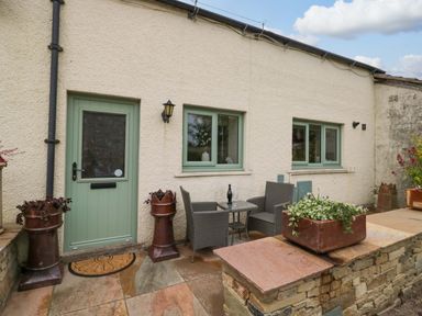 An outdoor seating area with a table and chairs at Yeat Stoup Cottage in Cockermouth
