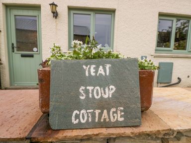 A sign indicating Yeat Stoup Cottage outside a building in Cockermouth