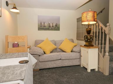 A living room with a sofa and staircase at Yeat Stoup Cottage Cockermouth