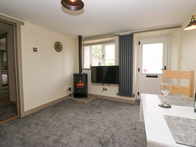 A living room with a wood stove and television at Yeat Stoup Cottage in Cockermouth