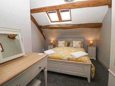 A bedroom with a bed and dressing table at Yeat Stoup Cottage Cockermouth