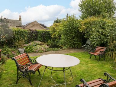 A garden with a table and chairs at Yeat Stoup Cottage in Cockermouth