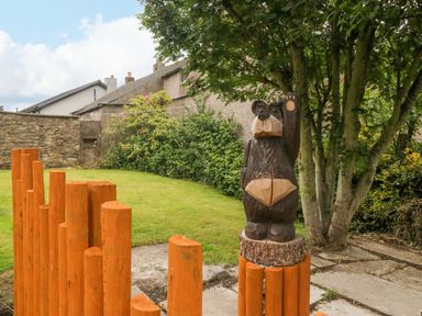 A wooden bear sculpture in a garden at Yeat Stoup Cottage Cockermouth