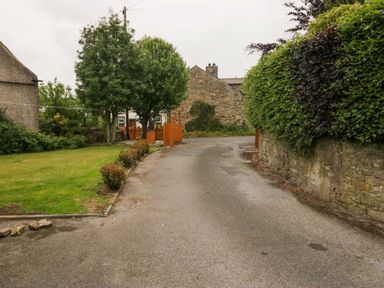 A road bordered by grass and trees at Yeat Stoup Cottage in Cockermouth