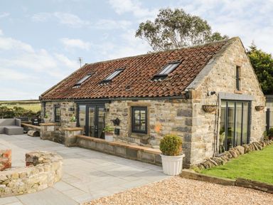 Stone cottage with tiled roof patio area and outdoor seating at Cowshed Normanby near Flyingthorpe