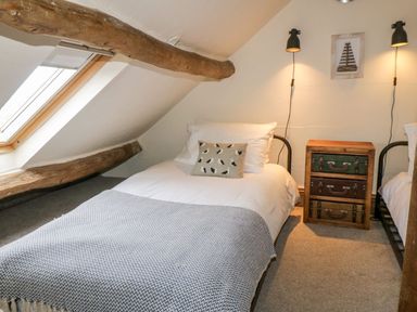 A bedroom with two single beds bedside table with drawers and two wall lamps at Cowshed Normanby near Flyingthorpe