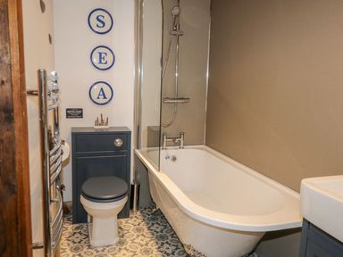 A bathroom with a bathtub shower toilet and sink at Cowshed Normanby near Flyingthorpe