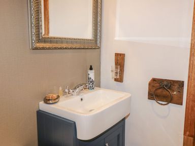 A bathroom sink with a silver faucet soap dispenser and mirror above at Cowshed Normanby near Flyingthorpe