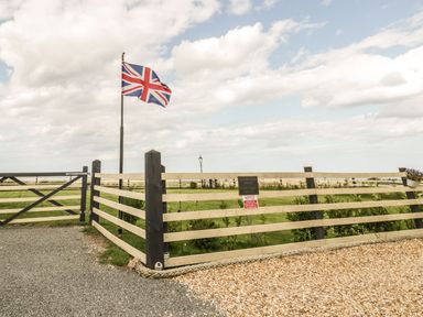 A fenced outdoor area with a Union Jack flag on a pole at Cowshed Normanby near Flyingthorpe