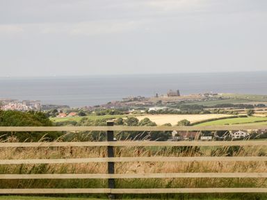 A countryside view with fields houses and a distant coastline with a historic building at Cowshed in Normanby near Flyingthorpe