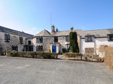A historic building with arched windows and a blue door with a gravel parking area in front at Alway in Lifton