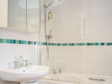 A bathroom with a sink and bathtub with a showerhead and a grab bar on the wall at The Barn in Lifton