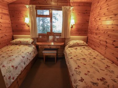 A bedroom with two single beds a wooden dressing table and a window at Goldcrest Withern near Alford