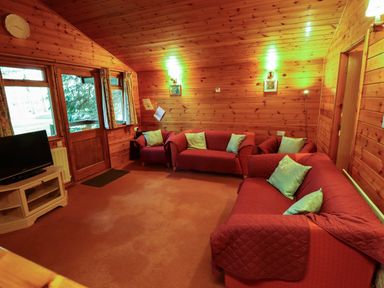 A living room with red sofas and light blue cushions in a wooden cabin at Partridge in Withern near Alford