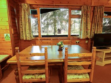 A dining area with wooden table and chairs and a TV on a stand at Partridge in Withern near Alford
