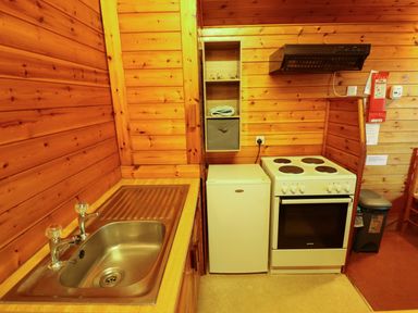 A small kitchen with a stainless steel sink white fridge electric stove wooden cabinets and a fire blanket at Partridge Withern near Alford