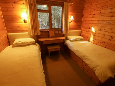 A wooden bedroom with two single beds and a small desk with a stool at Partridge Withern near Alford