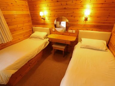 A bedroom with two single beds a wooden dressing table with a round mirror and wall lamps at Partridge in Withern near Alford