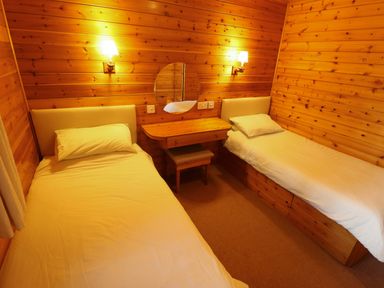 A bedroom with two single beds a wooden desk and a round mirror at Partridge in Withern near Alford