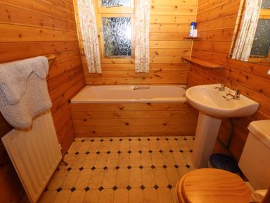 A bathroom with a bathtub a sink a toilet and wooden walls at Partridge in Withern near Alford