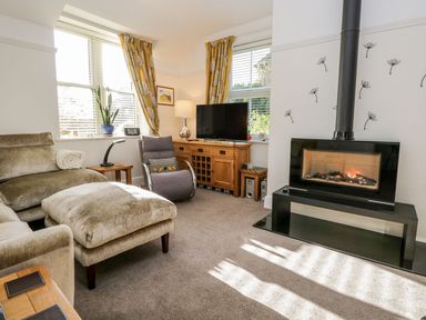 A living room with a sofa and armchair a television on a wooden cabinet and a fireplace at The Bolt Hole in Kendal