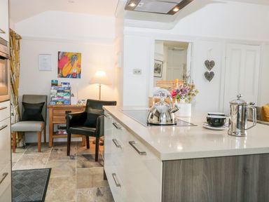 A kitchen with a kettle on a countertop and two chairs by a wooden table at The Bolt Hole in Kendal