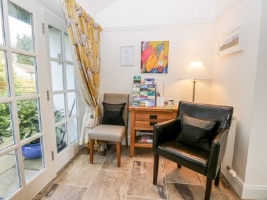 A corner with two chairs a wooden side table with brochures a lamp and artwork on the walls at The Bolt Hole in Kendal