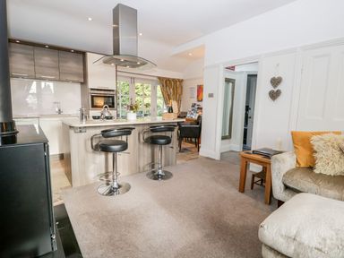 A kitchen and living area with bar stools a sofa and a wood stove at The Bolt Hole in Kendal