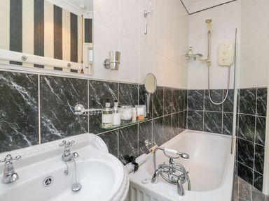 A bathroom with a sink and bathtub with a shower at The Bolt Hole in Kendal