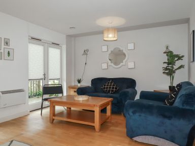 A living room with blue sofas wooden coffee table and plants at Treburgett in Porthtowan
