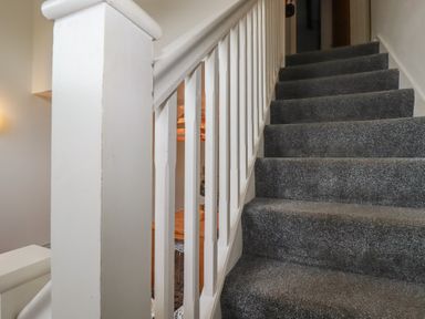 A staircase with gray carpet and white railing inside a house at Trenethick in Porthtowan