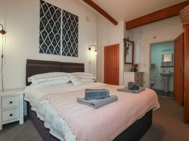 A bedroom with a double bed bedside tables and a door leading to a bathroom at Trenethick Porthtowan