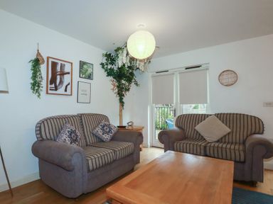 A sitting room with two striped sofas a wooden coffee table and framed pictures at Tregullan in Porthtowan