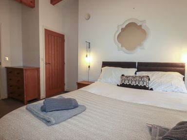 A bedroom with a double bed and folded towels on the blanket at Tregullan in Porthtowan