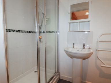 A bathroom with a shower enclosure pedestal sink and a wall-mounted towel rack at Tregullan in Porthtowan