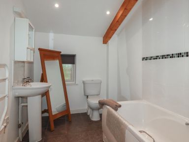 A bathroom with a sink toilet full-length mirror and bathtub with towel at Tregullan in Porthtowan