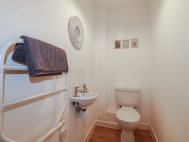 A small bathroom with a toilet sink towel rack and three framed pictures on the wall at Tregullan in Porthtowan