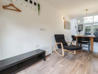 A dining area with a wooden table black chairs and a black armchair with wooden arms at Treveglos in Porthtowan