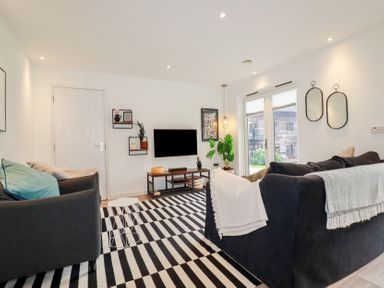 A living room with two sofas a striped rug a wall-mounted television and two mirrors at Treveglos in Porthtowan