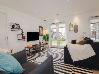 A living room with black and white striped rug sofas and a television at Treveglos in Porthtowan