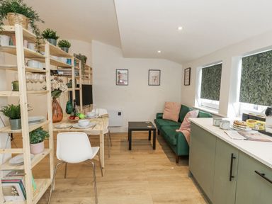 A living room with a dining area and kitchen appliances at Sea Pink Studio in Swanage