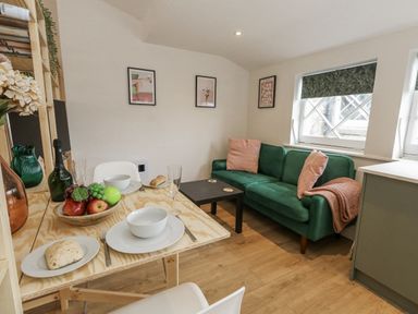 A living room with a sofa and dining table at Sea Pink Studio in Swanage