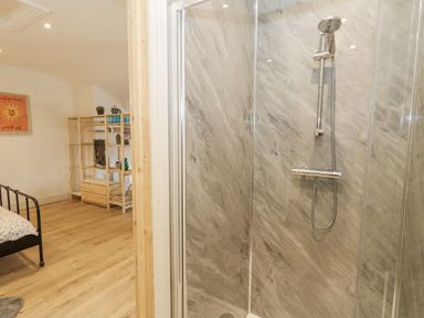 A bathroom with a shower and bed at Sea Pink Studio in Swanage