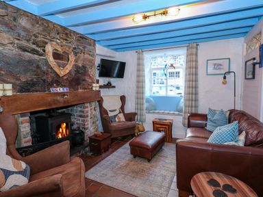 A living room with a stone fireplace and wood burning stove armchairs and a leather sofa at Llety in Beddgelert