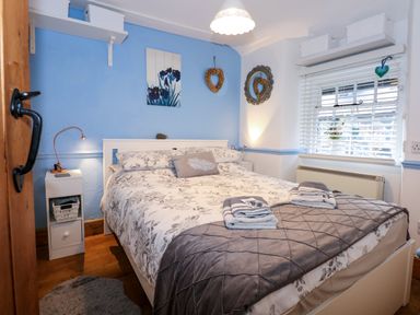 A bedroom with a bed placed against a blue and white wall with bedside tables and lamps at Llety in Beddgelert